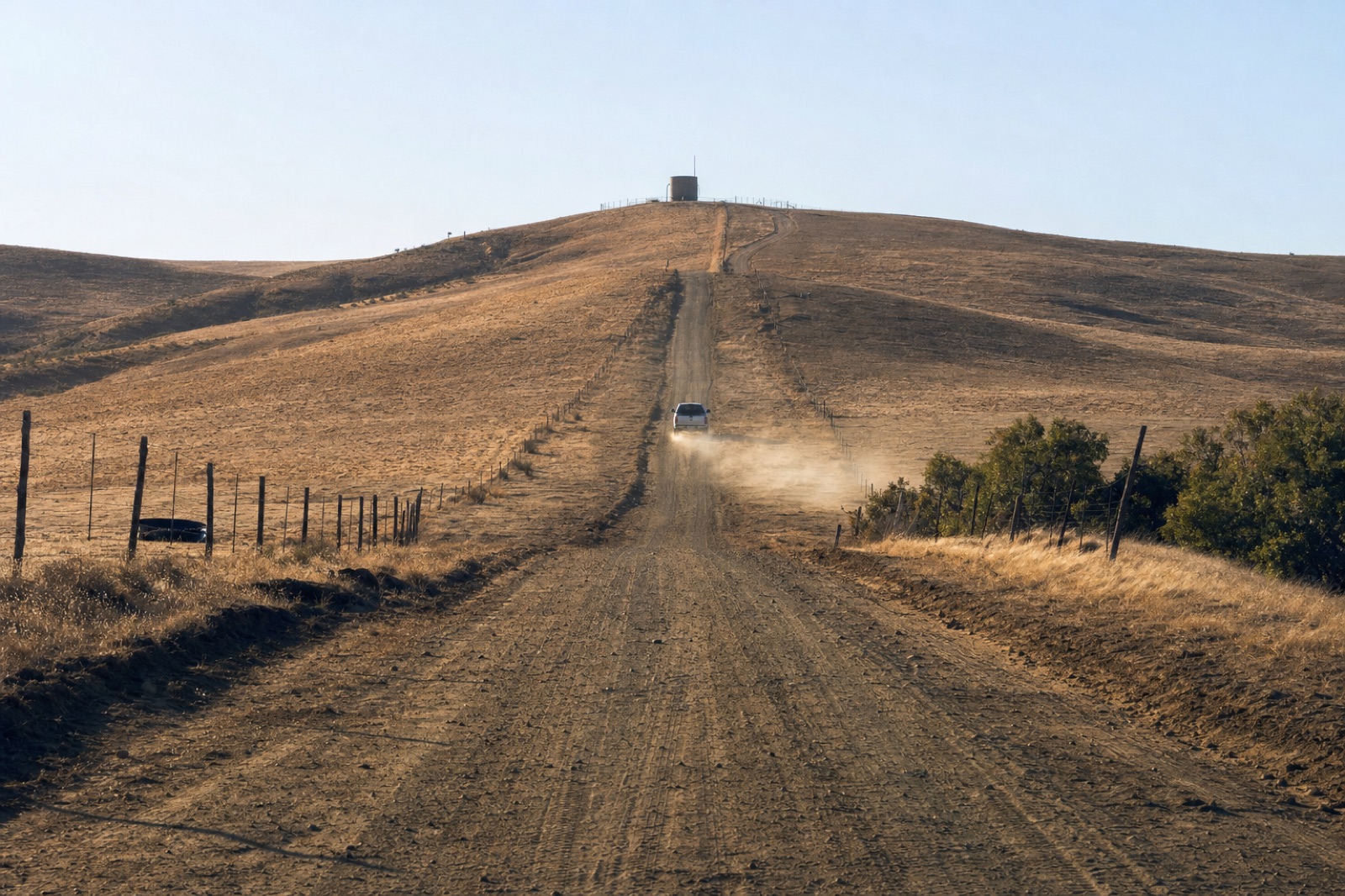 Ranch road climbing to a distant hilltop tank